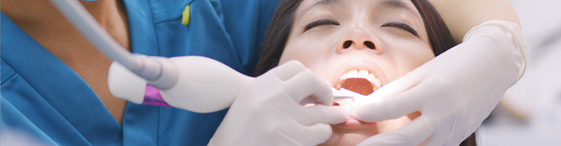 dentist using dental tools in woman's mouth.